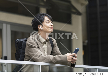 ヘッドホンをしてスマホを持った30代前半の男性 ヘッドホンをしてスマホを持った30代前半の男性 78090112
