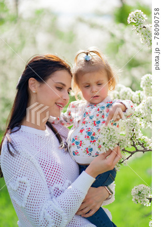 mom with a little daughter in her arms in the park by a flowering trees. mom with a little daughter in her arms in the park by a flowering trees. 78090758