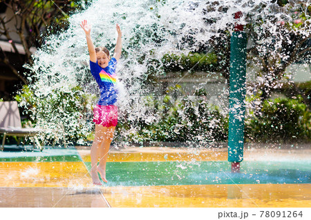 Child playing under tip bucket in water park. 78091264