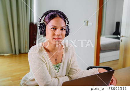 Beautiful young smiling asian woman working on laptop in living room at home. Asia business woman 78091511