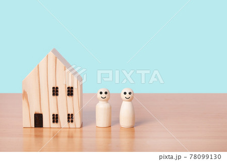 wooden doll couple stands in front of house model on blue background. 78099130
