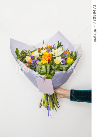 Hyacinths, yellow and orange tulips and white daffodils flowers in hand on white 78099473