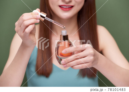 Beautiful young woman applying serum onto her healthy long hair at home 78101483