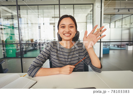 Easy-going woman sitting at table and waving her hand Easy-going woman sitting at table and waving her hand 78103383