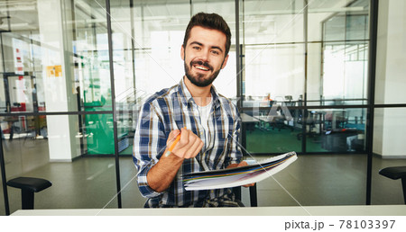 Expressive brunette man pointing pencil at the camera and smiling 78103397