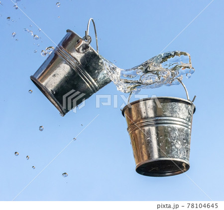 A pouring water from falling bucket to bucket, on a background of blue sky. 78104645