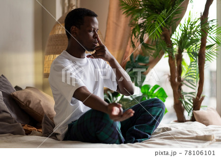Young african man practicing yoga lesson, doing Alternate Nostril Breathing exercise Young african man practicing yoga lesson, doing Alternate Nostril Breathing exercise 78106101