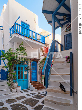 Traditional narrow cobbled streets, beautiful alleyways of Greek island towns. White houses, flower pots, blue balconies and doors. Mykonos, Greece 78106493