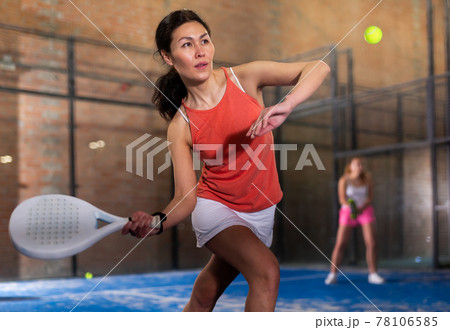 Concentrated asian woman playing paddle tennis indoors 78106585