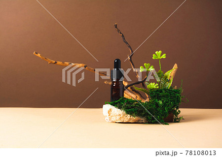 Serum and oil cosmetic bottle on a concrete stone podium with wooden branch, moss and green plants Serum and oil cosmetic bottle on a concrete stone podium with wooden branch, moss and green plants 78108013