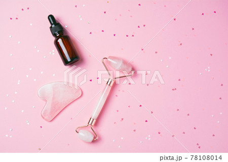 Roller and gua sha massage scraper and cometic product on a pink background Roller and gua sha massage scraper and cometic product on a pink background 78108014