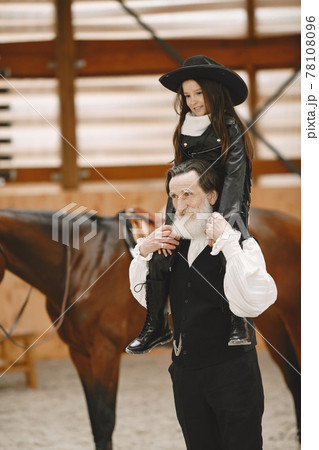 A little child riding a horse with an instructor 78108096