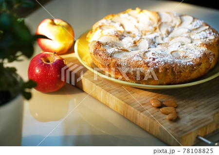 Apple pie sprinkled with icing sugar, red apples and almonds 78108825