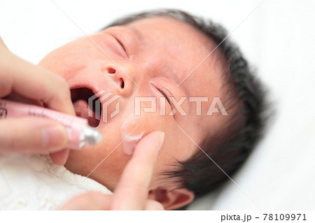 新生児の乳児湿疹に薬を塗るママの写真素材