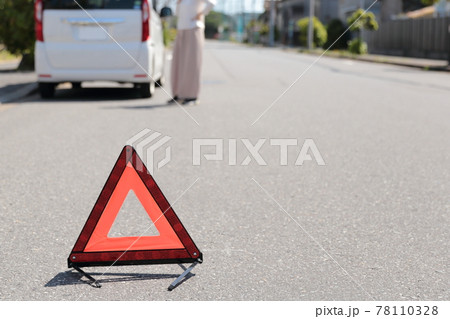 車が故障して三角停止表示版を置く女性 78110328