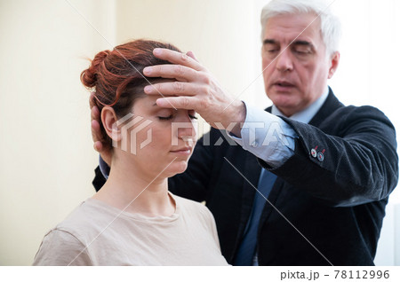 Mature gray-haired man hypnotizes Caucasian woman during hypnotherapy session. The psychologist uses alternative treatments for the subconscious mind 78112996
