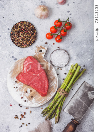 Slice of Raw Beef sirlion steak on round chopping board with tomatoes,garlic and asparagus tips and meat hatchet. Top view Slice of Raw Beef sirlion steak on round chopping board with tomatoes,garlic and asparagus tips and meat hatchet. Top view 78113253