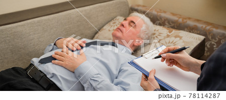 An elderly man lies on a couch during an appointment with a psychotherapist. An elderly male patient in an individual consultation with a female psychologist An elderly man lies on a couch during an appointment with a psychotherapist. An elderly male patient in an individual consultation with a female psychologist 78114287