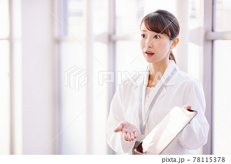 フレーム外の人物にタブレット端末の画面を見せる医療従事者の女性 フレーム外の人物にタブレット端末の画面を見せる医療従事者の女性 78115378