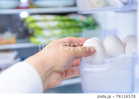 料理のために冷蔵庫から卵を取り出す男性の手　扉を開けた冷蔵庫　 78116578