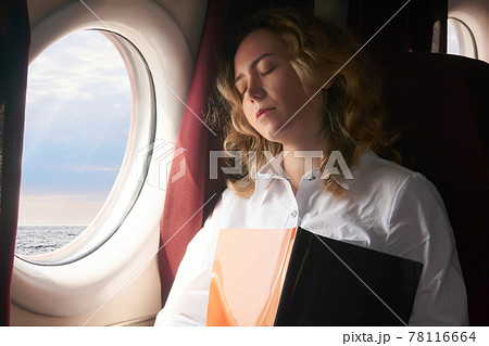 young woman dozed off in the cabin of an airplane flying low above the sea surface, or some high-speed vessel young woman dozed off in the cabin of an airplane flying low above the sea surface, or some high-speed vessel 78116664