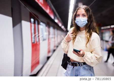 Young woman in mask using mobile phone while waiting metro Young woman in mask using mobile phone while waiting metro 78116865