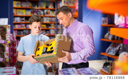 Cheery teenage boy with father buying toy car Cheery teenage boy with father buying toy car 78116866