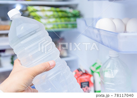 冷蔵庫のドアポケットから水のペットボトルを取り出す男性 扉を開けた冷蔵庫 冷蔵庫のドアポケットから水のペットボトルを取り出す男性 扉を開けた冷蔵庫 78117040