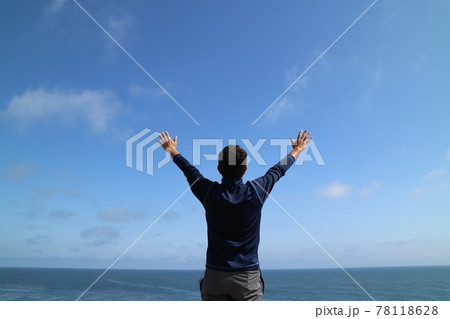 海と空に向かって両手を広げる男性のうしろ姿 78118628