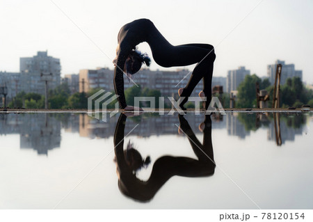 Silhouette of flexible and fit girl bending her back. Concept of yoga and healthy lifestyle Silhouette of flexible and fit girl bending her back. Concept of yoga and healthy lifestyle 78120154