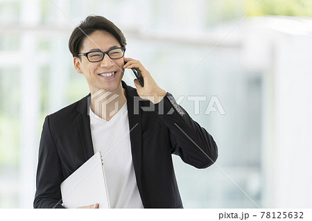 スマートフォンをで通話する眼鏡をかけた30代の男性 カジュアルビジネス イメージ スマートフォンをで通話する眼鏡をかけた30代の男性 カジュアルビジネス イメージ 78125632