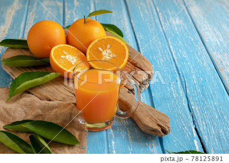 Fresh orange and a glass of orange juice on a wooden table background Fresh orange and a glass of orange juice on a wooden table background 78125891