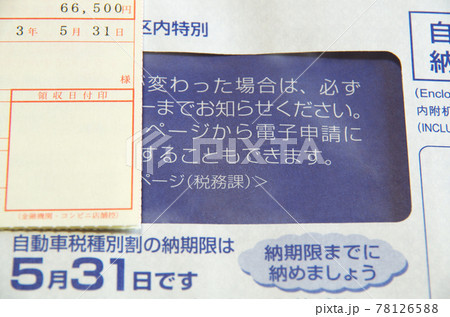 自動車税の納税通知書が届いて開封して納付書を取り出して税額を確認している光景 78126588