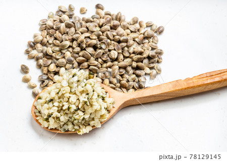 cores in wood spoon and pile of hemp seeds on gray cores in wood spoon and pile of hemp seeds on gray 78129145