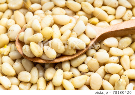 wood spoon with shelled pine nuts on pile of nuts 78130420