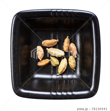 several cardamom pods in black bowl isolated several cardamom pods in black bowl isolated 78130541