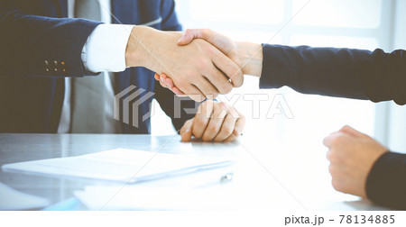 Businesspeople or lawyers shaking hands finishing up a meeting in blue toned office , close-up. Success at negotiation and handshake concepts 78134885