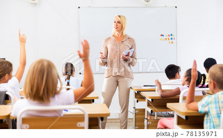Woman teacher standing at whiteboard during lesson with tweens Woman teacher standing at whiteboard during lesson with tweens 78135971