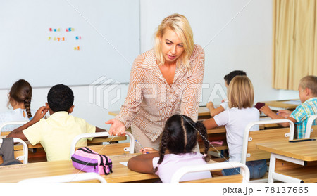 Woman teacher helping pupil explaining new theme 78137665