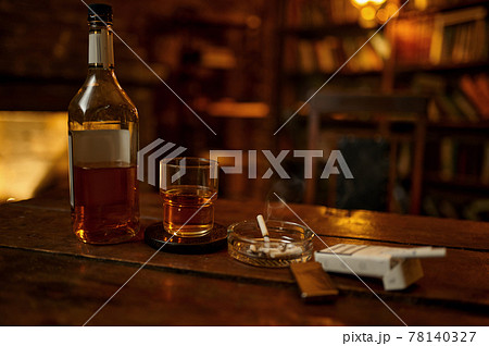 Cigarette in ashtray and alcohol on wooden table Cigarette in ashtray and alcohol on wooden table 78140327