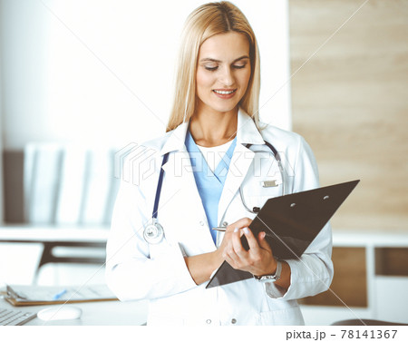 Woman-doctor controls medication history record and medical exam results. at black clipboard. Medicine concept Woman-doctor controls medication history record and medical exam results. at black clipboard. Medicine concept 78141367
