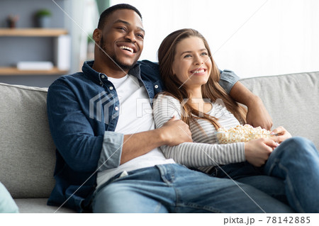Home Date. Interracial Couple Relaxing On Couch, Watching Tv And Eating Popcorn Home Date. Interracial Couple Relaxing On Couch, Watching Tv And Eating Popcorn 78142885