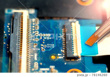 Connecting a flex cable to the laptop motherboard with tweezers, laptop repair in a service center Connecting a flex cable to the laptop motherboard with tweezers, laptop repair in a service center 78146260