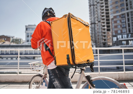 Man with backpack with food looking route at his smartphone app while riding to the client Man with backpack with food looking route at his smartphone app while riding to the client 78146893