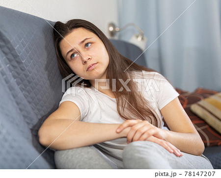 Depressed young woman sitting on sofa at home Depressed young woman sitting on sofa at home 78147207