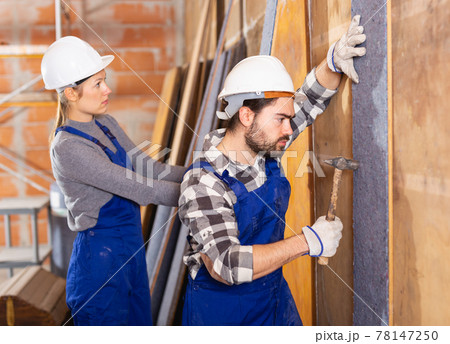 Two professional builders sheathe walls with insulation Two professional builders sheathe walls with insulation 78147250