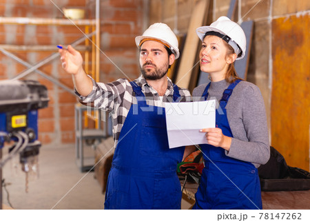 Workers man and woman discuss construction plan Workers man and woman discuss construction plan 78147262