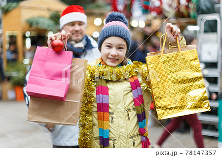Smiling girl with father holding shopping bags Smiling girl with father holding shopping bags 78147357
