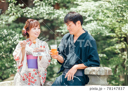 夏祭りにきてビールやたこ焼きを食べる男女 78147837