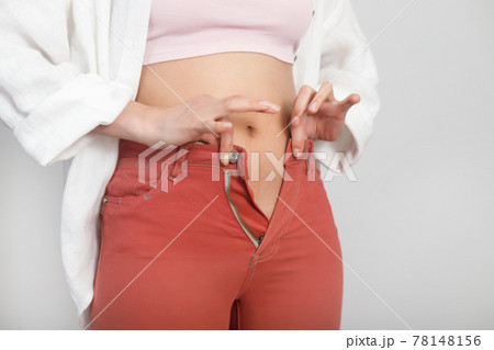 Close-up of belly young woman cannot wear summer pants. Diet, overweight, obesity concept 78148156